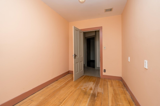 empty room featuring light wood-style flooring, visible vents, and baseboards