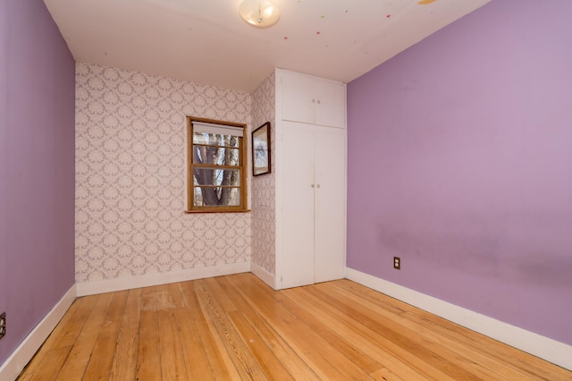 spare room featuring light wood-type flooring, baseboards, and wallpapered walls