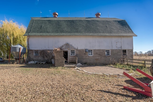 rear view of house featuring a barn, roof with shingles, fence, and an outdoor structure