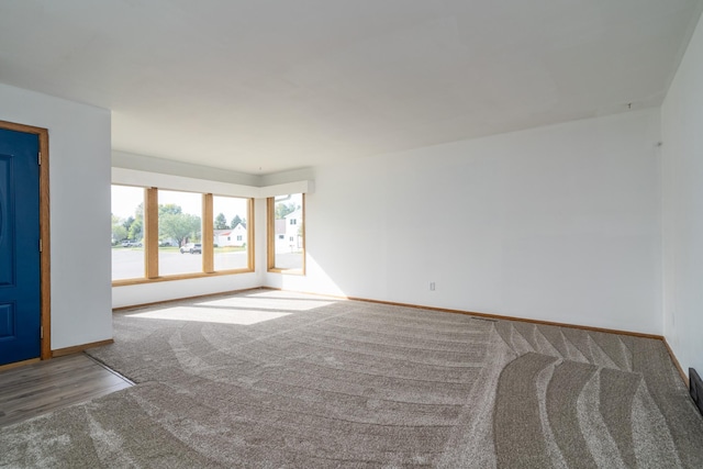 carpeted empty room featuring baseboards