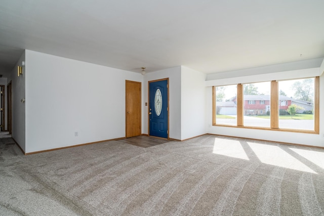 unfurnished living room featuring carpet and baseboards