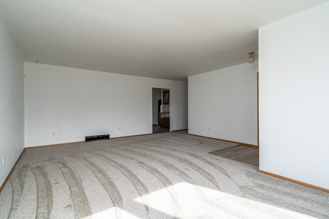 carpeted spare room with baseboards and visible vents