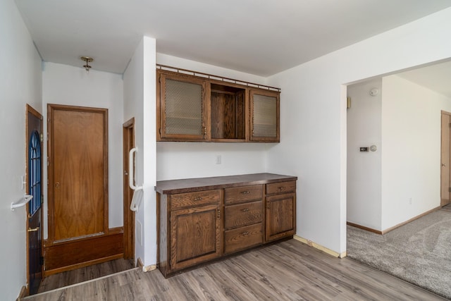 kitchen with light wood-style floors, dark countertops, and baseboards