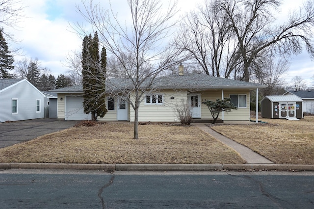 ranch-style house featuring driveway, an attached garage, a storage unit, and an outdoor structure