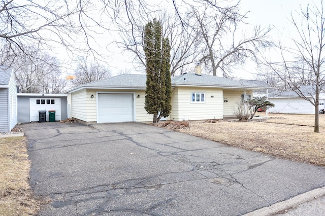 single story home featuring a garage, driveway, roof with shingles, and a chimney