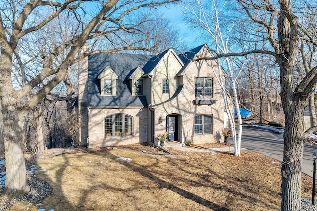 view of front of property featuring brick siding, driveway, and a shingled roof