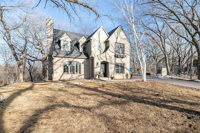 view of front facade featuring brick siding and a chimney