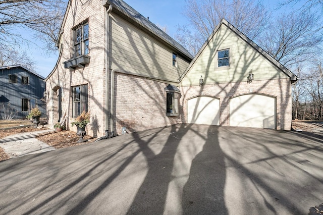 view of home's exterior featuring aphalt driveway, brick siding, and a garage