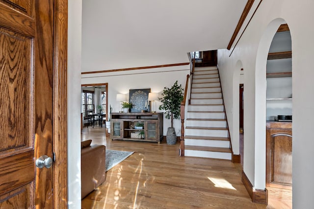 stairs featuring arched walkways, baseboards, and wood finished floors