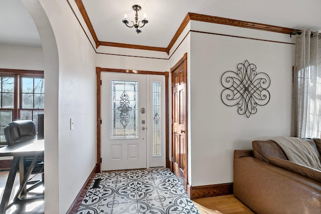 entrance foyer featuring light tile patterned flooring, baseboards, arched walkways, and ornamental molding