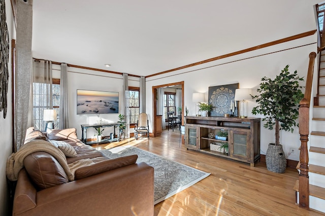 living room featuring a wealth of natural light, stairway, ornamental molding, and wood finished floors