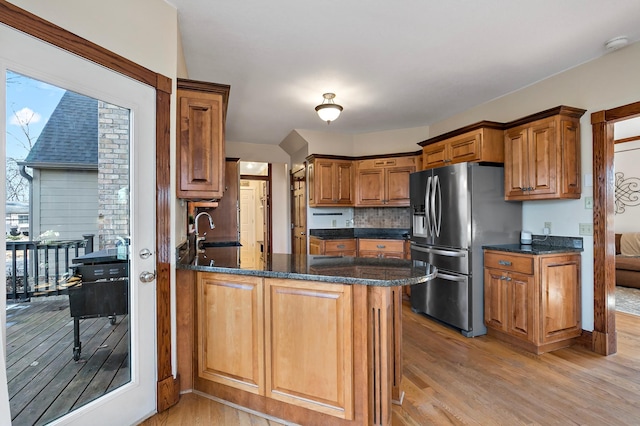 kitchen featuring stainless steel fridge with ice dispenser, a peninsula, light wood-style floors, brown cabinetry, and a sink