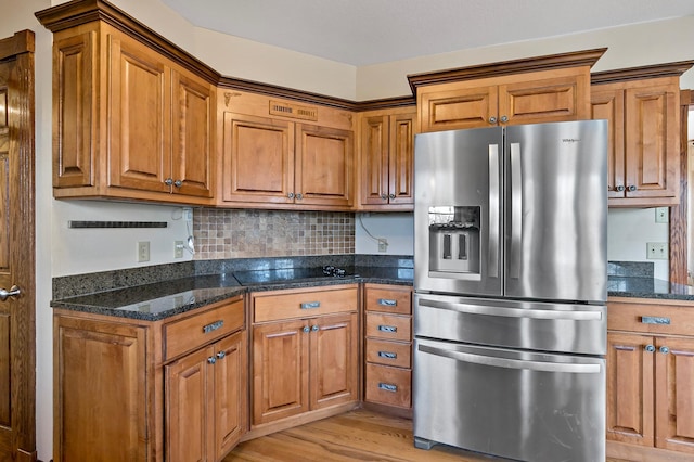 kitchen featuring dark stone countertops, stainless steel fridge with ice dispenser, and brown cabinets