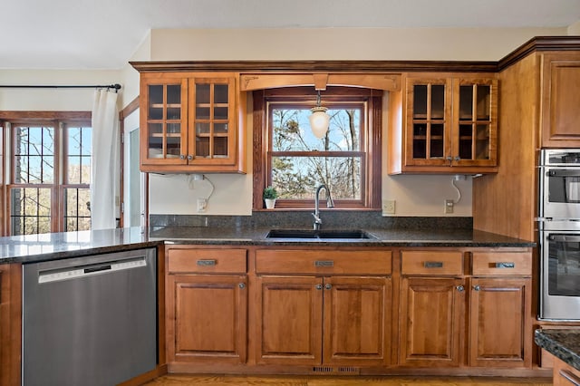 kitchen featuring a sink, stainless steel appliances, brown cabinets, and a healthy amount of sunlight