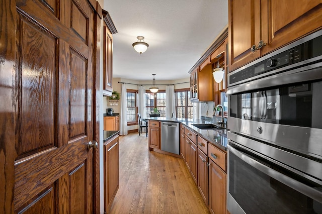 kitchen featuring light wood-style floors, brown cabinets, appliances with stainless steel finishes, and a sink