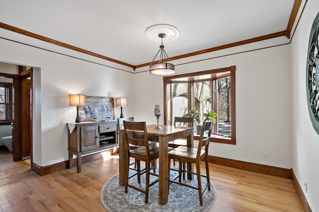 dining area featuring light wood-style flooring, baseboards, and ornamental molding