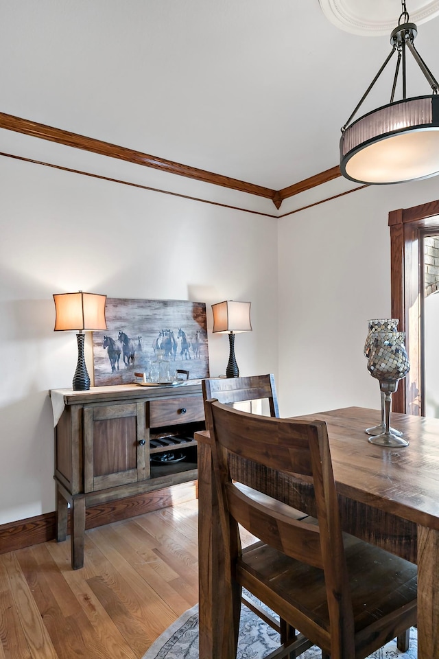 dining space featuring light wood-style flooring, baseboards, and ornamental molding