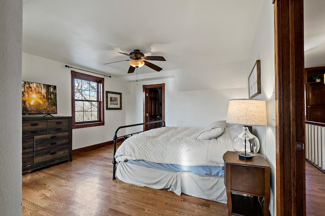 bedroom featuring ceiling fan, baseboards, and wood finished floors