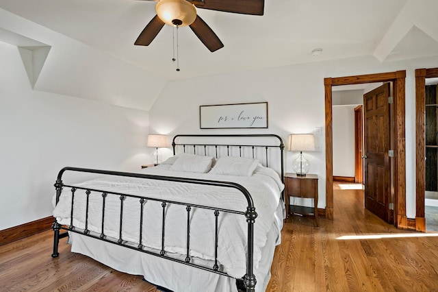 bedroom featuring baseboards, lofted ceiling, wood finished floors, and a ceiling fan