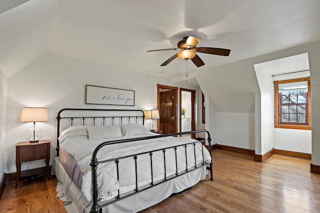 bedroom featuring baseboards, lofted ceiling, and wood finished floors