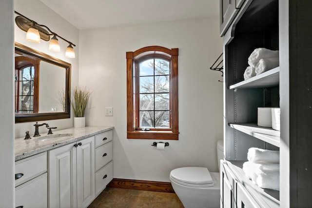 bathroom featuring baseboards, toilet, and vanity