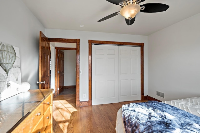 bedroom with wood finished floors, visible vents, a closet, and baseboards