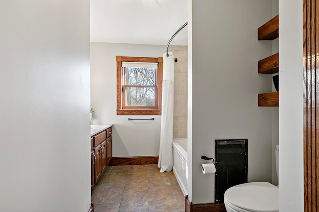 full bathroom with stone finish flooring, baseboards, toilet, shower / bath combo, and vanity