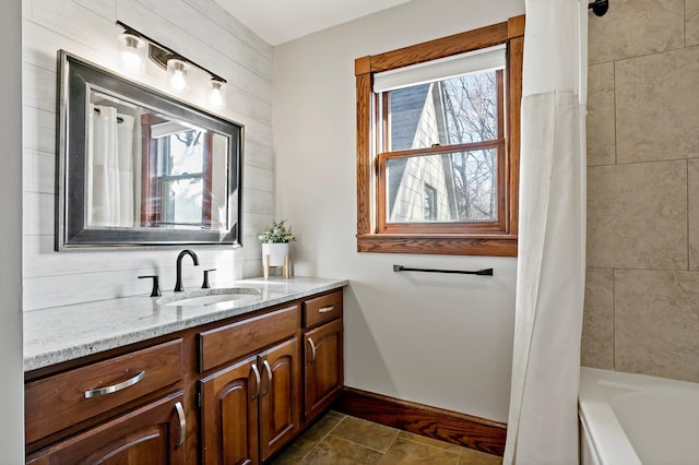 bathroom with vanity, shower / bath combo with shower curtain, and baseboards