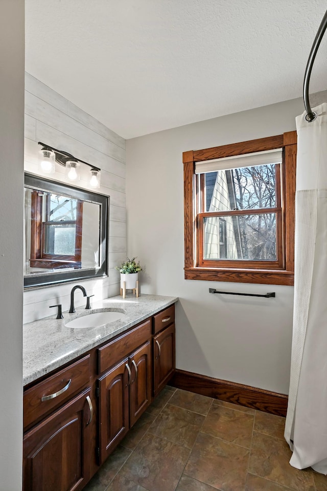 bathroom with vanity, baseboards, and stone finish flooring