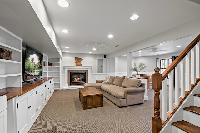 carpeted living area with a glass covered fireplace, stairway, recessed lighting, and a ceiling fan