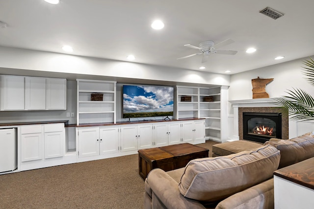 living room with a glass covered fireplace, recessed lighting, visible vents, and dark colored carpet