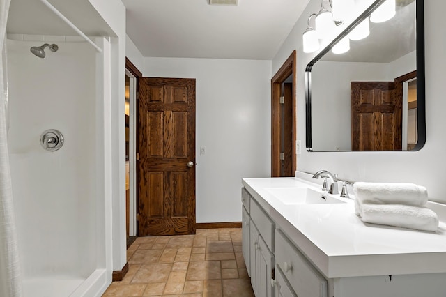 full bathroom featuring stone tile flooring, a shower stall, vanity, and baseboards