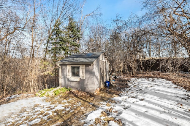 snow covered structure with an outbuilding and a storage unit