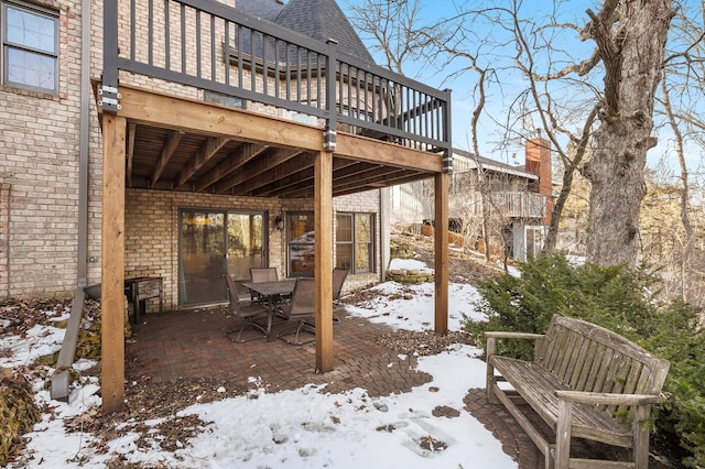 snow covered patio with a deck and outdoor dining space