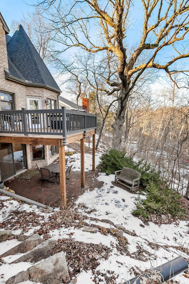 yard layered in snow featuring a deck and a patio area