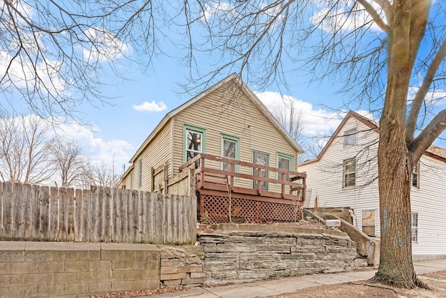 rear view of house with fence and a wooden deck