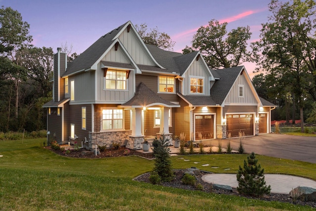 craftsman inspired home with stone siding, board and batten siding, a front yard, and driveway