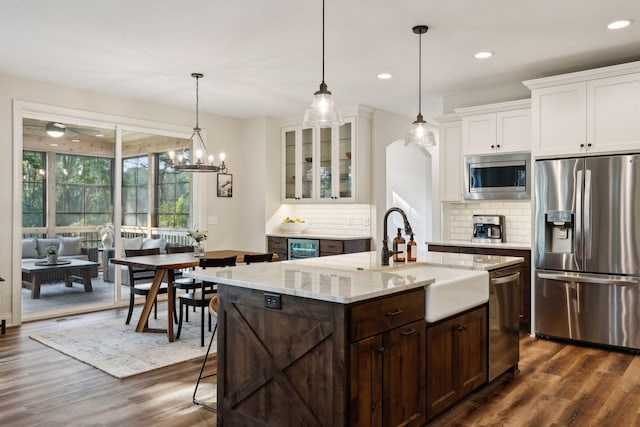 kitchen featuring glass insert cabinets, dark wood-style flooring, stainless steel appliances, white cabinetry, and a sink