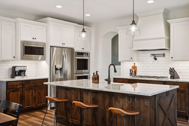 kitchen featuring dark wood-style floors, custom range hood, stainless steel appliances, white cabinetry, and a sink