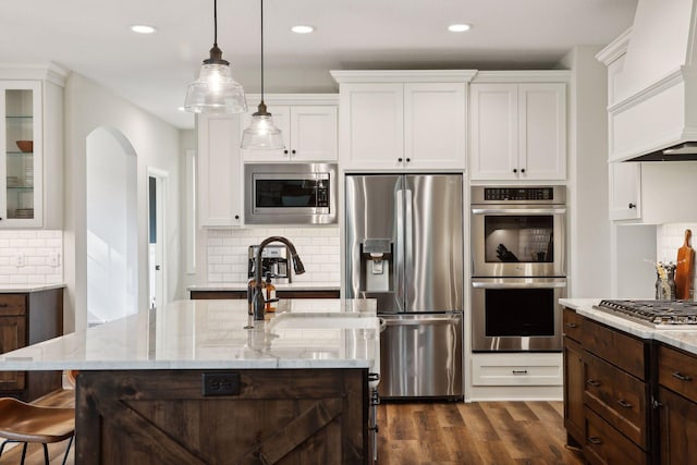 kitchen with a breakfast bar area, stainless steel appliances, premium range hood, dark wood-style flooring, and white cabinetry