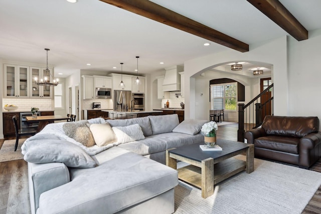 living room featuring dark wood-style floors, arched walkways, beamed ceiling, and stairs