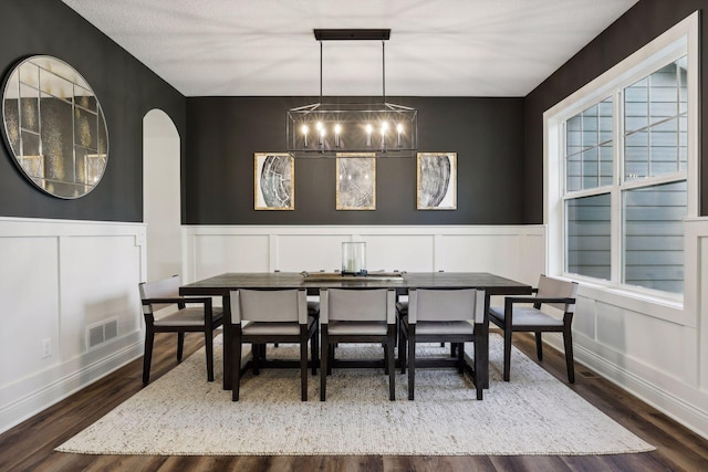 dining area featuring a wainscoted wall, wood finished floors, visible vents, and a healthy amount of sunlight