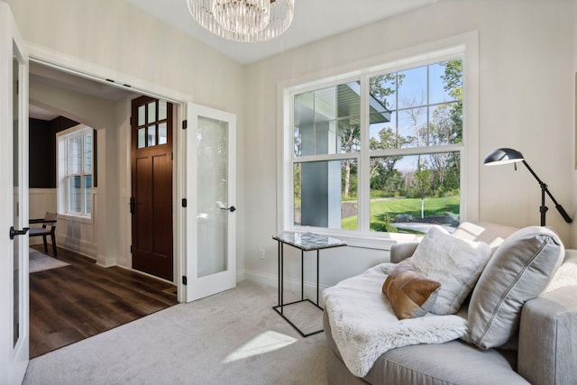 sitting room featuring a healthy amount of sunlight, carpet, baseboards, and a notable chandelier