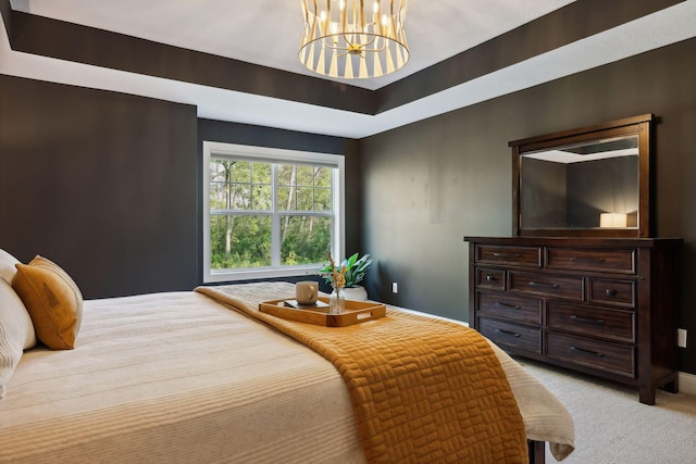 bedroom with a tray ceiling, light colored carpet, and a notable chandelier