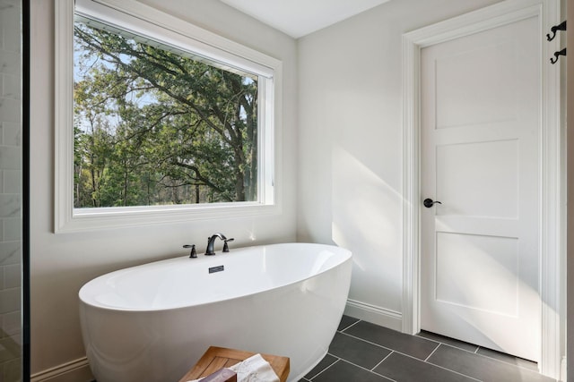 bathroom with a soaking tub and tile patterned flooring