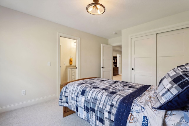 bedroom with a closet, light carpet, baseboards, and ensuite bathroom