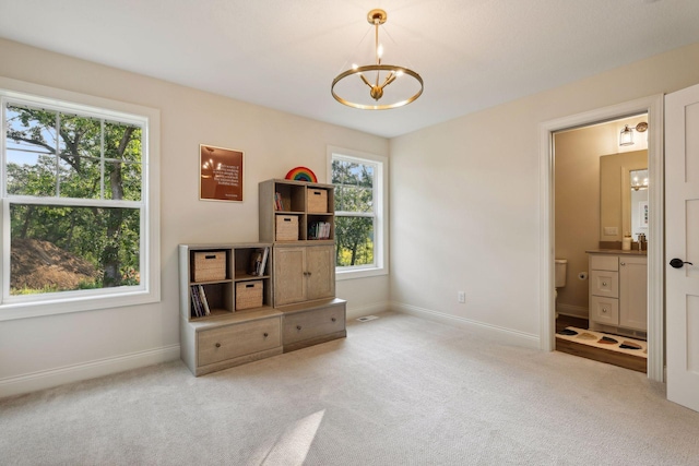 carpeted bedroom featuring ensuite bath, baseboards, and an inviting chandelier