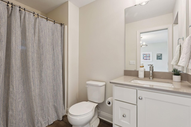 bathroom featuring toilet, baseboards, and vanity