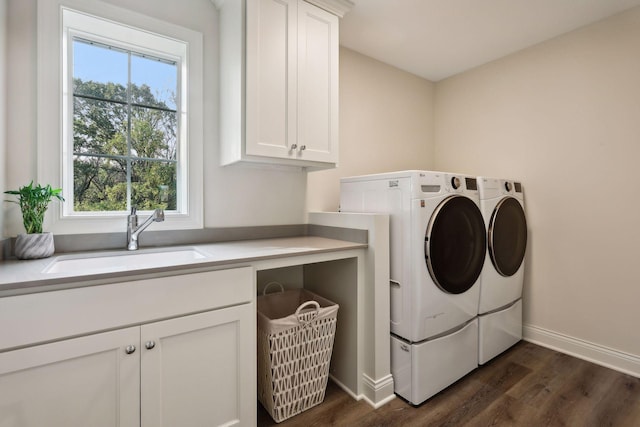 clothes washing area with dark wood-style flooring, washing machine and clothes dryer, a sink, and cabinet space