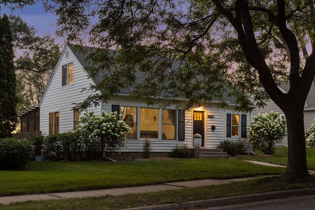 view of front of house with a lawn and roof with shingles